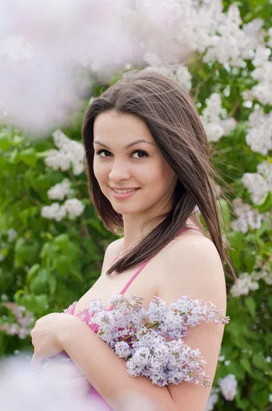 Joven bonita mujer oliendo rosa lila — Foto de Stock