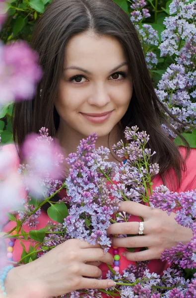 Young pretty woman smelling pink lilac — Stock Photo, Image