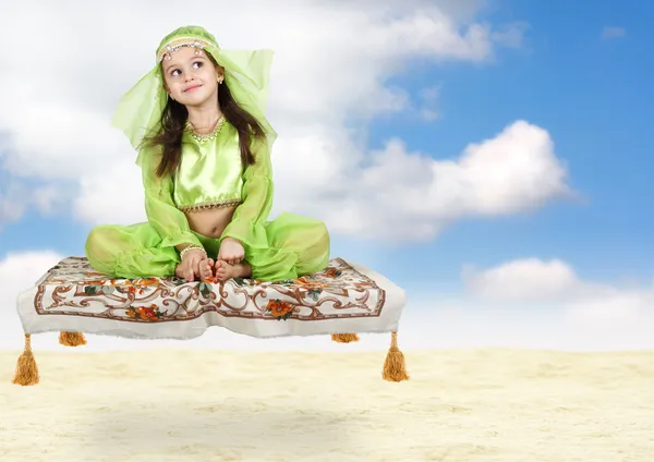 Kleines arabisches Mädchen sitzt auf fliegendem Teppich — Stockfoto
