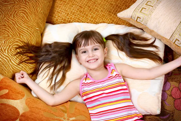 Glückliches Mädchen, das sich auf weichem Kissen ausruht — Stockfoto