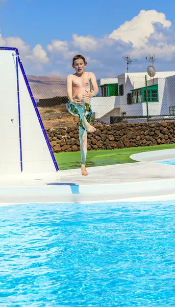파란 수영장에서 점프 하는 소년 — 스톡 사진