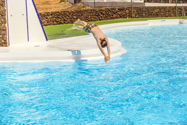 Junge springt in den blauen Pool — Stockfoto