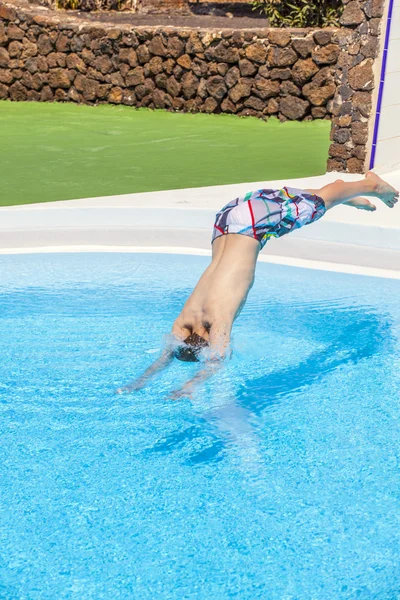 Chłopiec skoki w puli niebieski — Zdjęcie stockowe