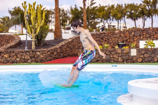 Pojken hoppar i blå poolen — Stockfoto