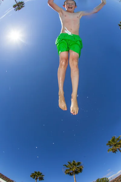 Jongen springen in het blauwe zwembad — Stockfoto