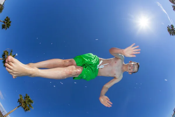 Хлопчик стрибає у блакитному басейні — стокове фото