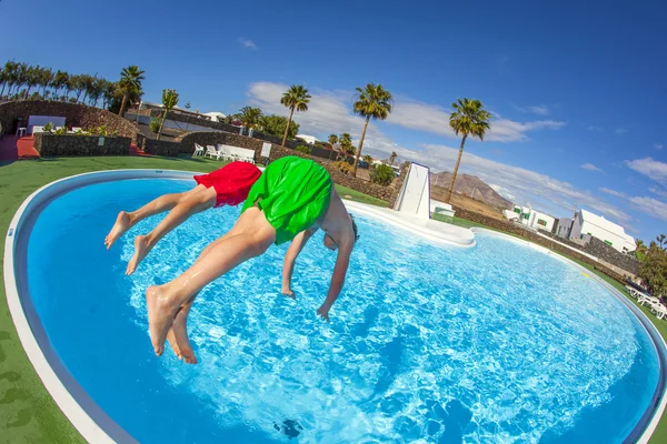 Ragazzo che salta nella piscina blu — Foto Stock