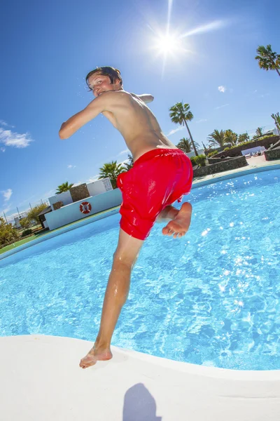Jongen springen in het blauwe zwembad — Stockfoto