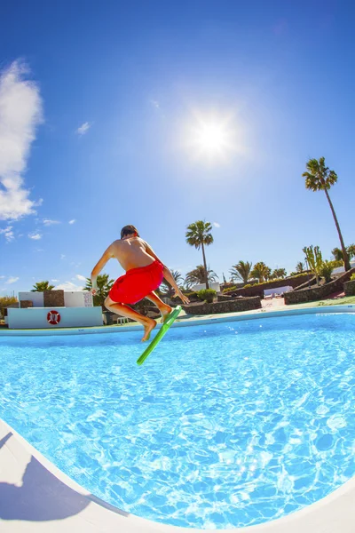 Garçon sautant dans la piscine bleue — Photo