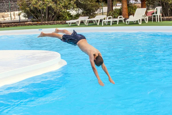 Мальчик прыгает в голубой бассейн — стоковое фото
