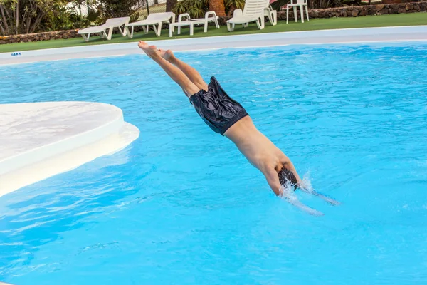 Garçon sautant dans la piscine bleue — Photo