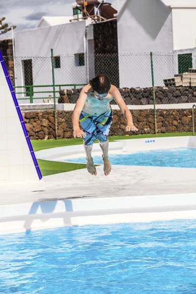 Ragazzo che salta nella piscina blu — Foto Stock