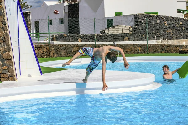 Chico saltando en la piscina azul — Foto de Stock