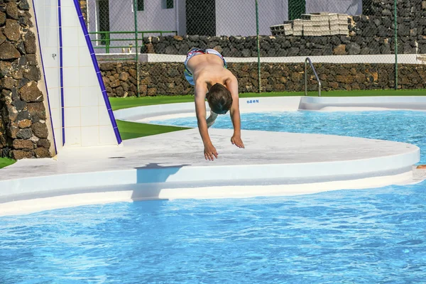 Chico saltando en la piscina azul — Foto de Stock