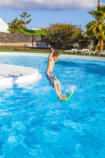 Rapaz a saltar para a piscina azul — Fotografia de Stock