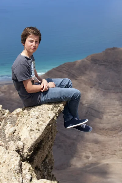 Pojken sitter på en sten — Stockfoto
