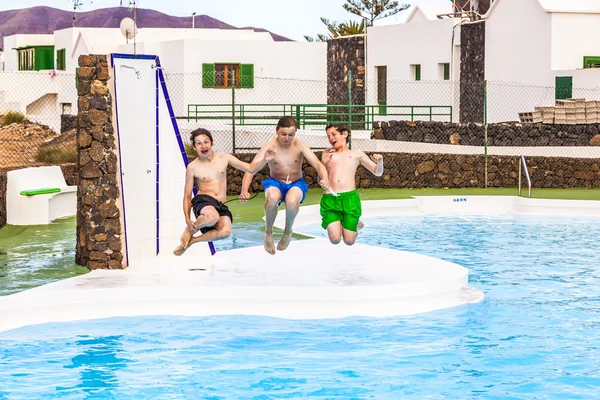 Tres chicos saltando en la piscina — Foto de Stock