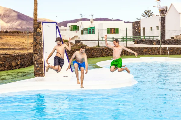 Tre ragazzi che saltano in piscina — Foto Stock