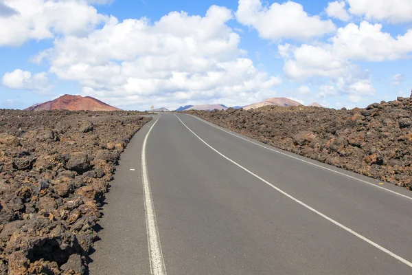 Road through lava rocks and volcanic mountains. Los Hervideros. — Stock Photo, Image
