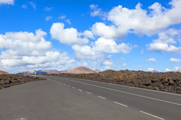 Road through lava rocks and volcanic mountains. Los Hervideros. — Stock Photo, Image