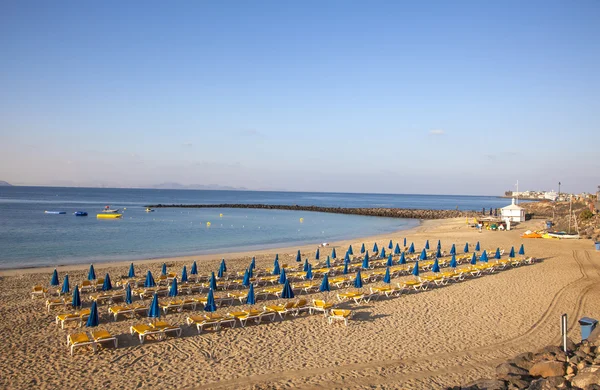 Playa de arena por la mañana con camas de playa y sombrilla — Foto de Stock