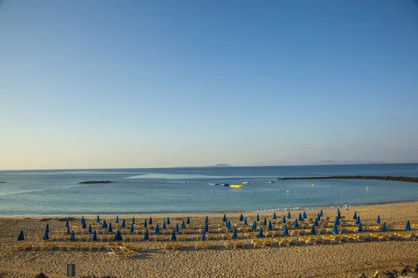 Praia de areia de manhã com camas de praia e guarda-chuva — Fotografia de Stock