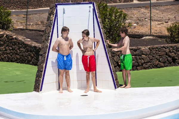 Chlapci unter fond sprchapojkar har roligt unter pool dusch — Stockfoto
