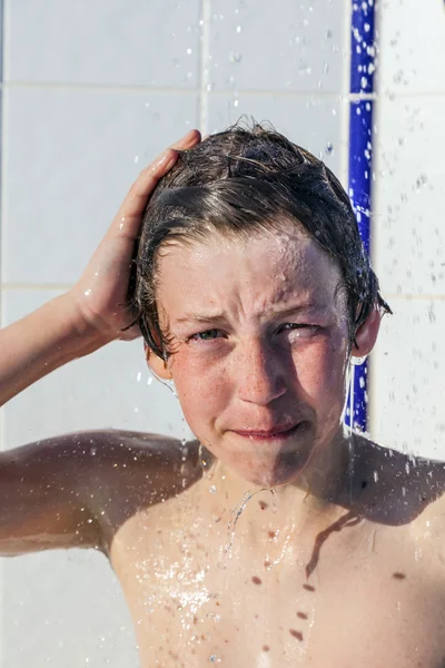 Garoto se diverte unter o chuveiro da piscina — Fotografia de Stock