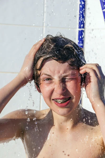 Pojken har kul unter pool dusch — Stockfoto