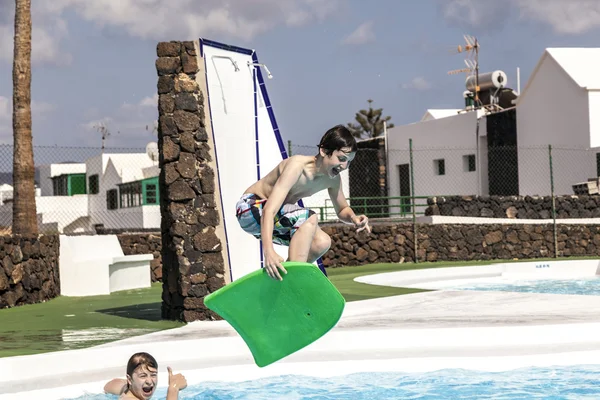 Chico saltando en la piscina con la tabla de surf —  Fotos de Stock