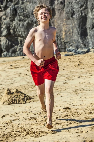Chłopiec jest uruchomiony na plaży w słoneczny dzień — Zdjęcie stockowe