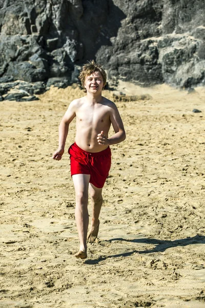 Мальчик бегает по пляжу в солнечный день — стоковое фото