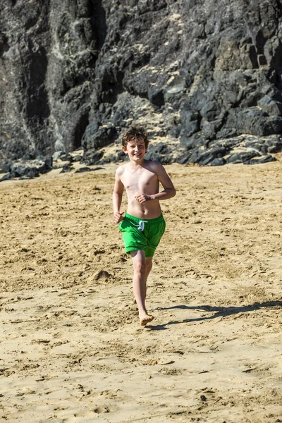 Garçon court sur la plage par une journée ensoleillée — Photo