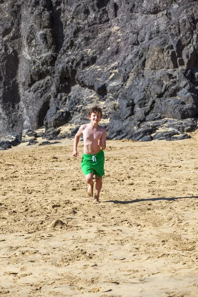 Αγόρι εκτελείται στην παραλία μια ηλιόλουστη ημέρα — Φωτογραφία Αρχείου
