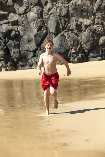 Chico está corriendo en la playa en un día soleado —  Fotos de Stock