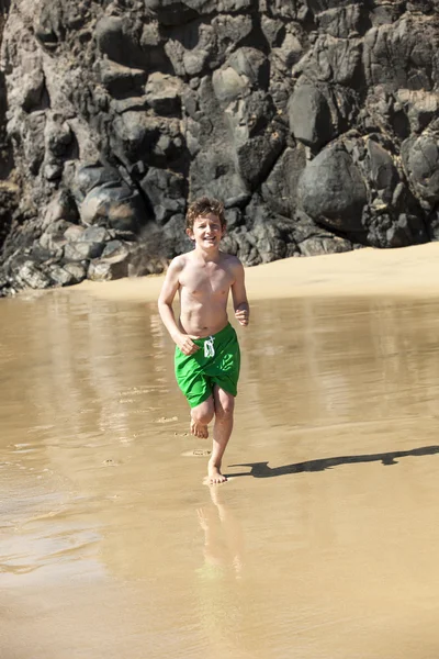 Menino está correndo na praia em um dia ensolarado — Fotografia de Stock