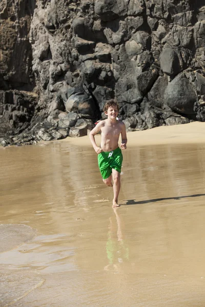 Garçon court sur la plage par une journée ensoleillée — Photo