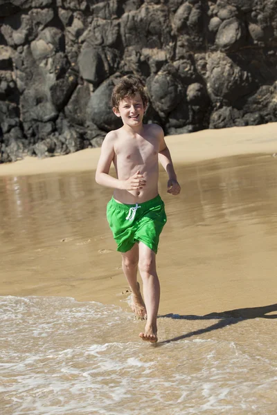 Хлопчик біжить на пляжі в сонячний день — стокове фото
