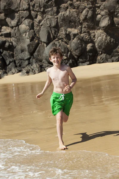 Chico está corriendo en la playa en un día soleado —  Fotos de Stock