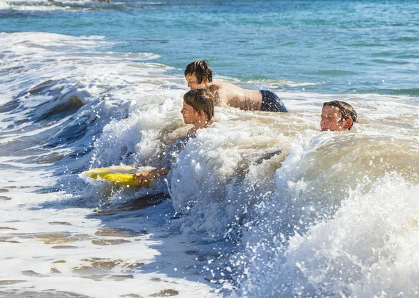 Rapazes divirtam-se a surfar nas ondas — Fotografia de Stock