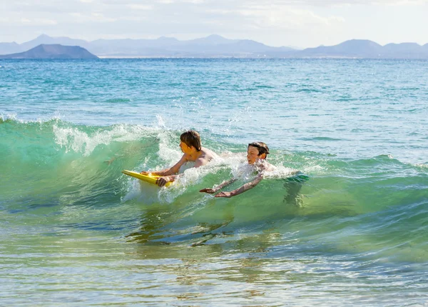 Rapazes divirtam-se a surfar nas ondas — Fotografia de Stock