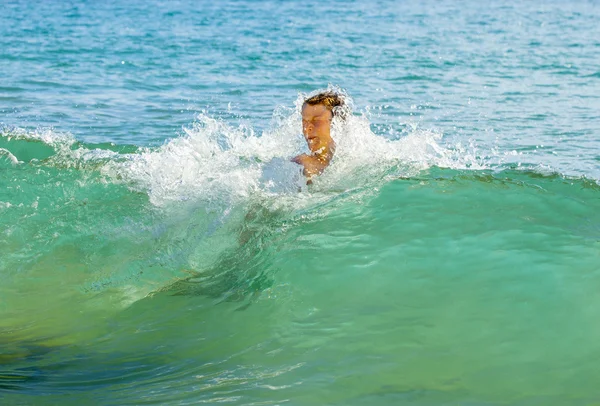 Jongen heeft leuke springen in de golven — Stockfoto
