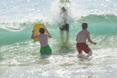 Çocuklar eğlenceli dalgalarda sörf