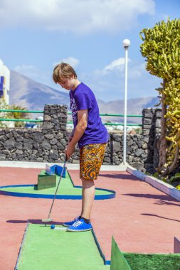 Oğlan mini golf oynamayı seviyor.