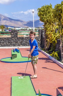 Oğlan mini golf oynamayı seviyor.