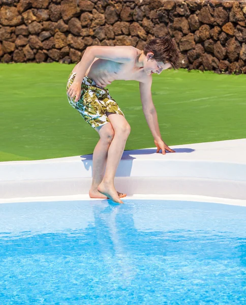 Menino testando a temperatura da água da piscina — Fotografia de Stock