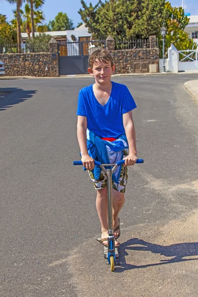 男孩骑踏板车在大街上 — 图库照片