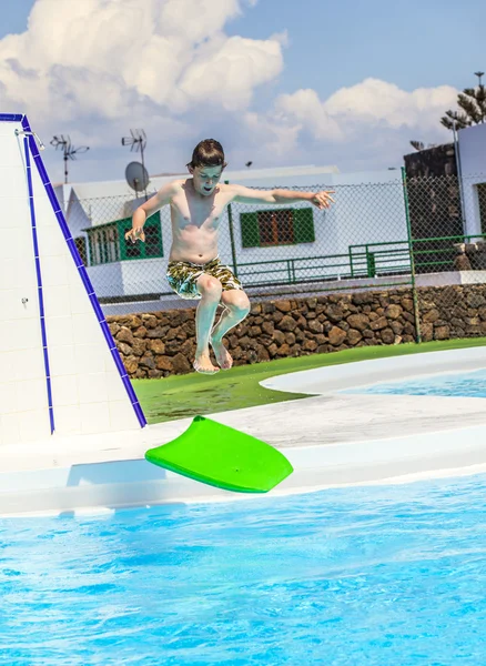 Junge springt in den blauen Pool — Stockfoto