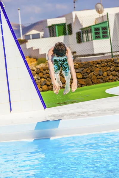 Мальчик прыгает в голубой бассейн — стоковое фото