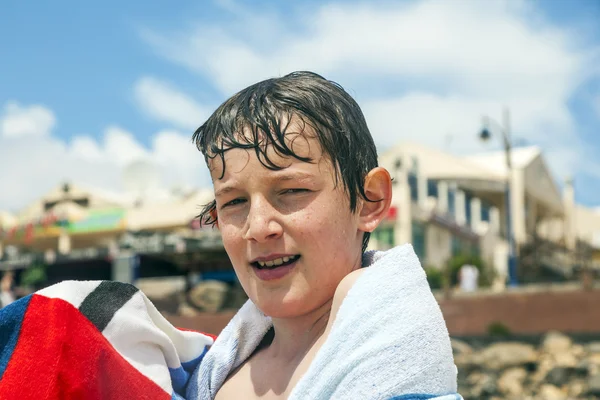 Lycklig pojke med en handduk på stranden — Stockfoto